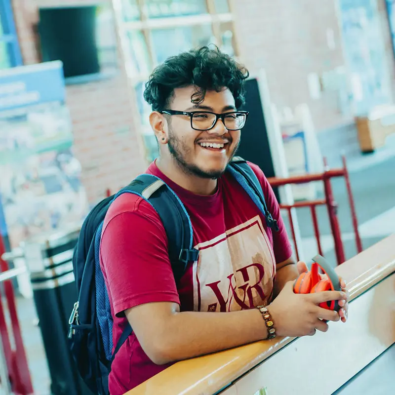 Student smiling holding headphones at UMass Lowell Orientation.