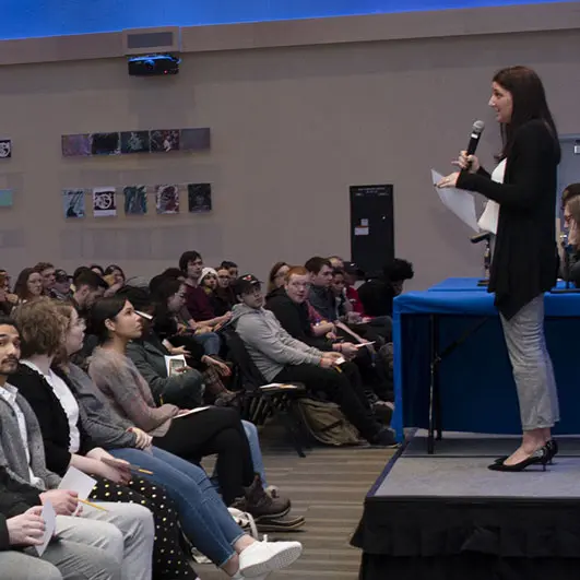 Woman with microphone speaks to crowded room
