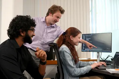 Said Siddiqui, John Ohrn and Amelia Halloran crowd around a computer screen.