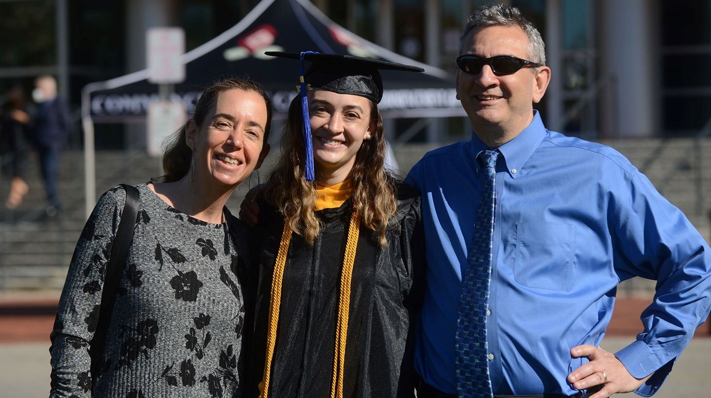 Mom, graduate and dad in front of Tsongas Center