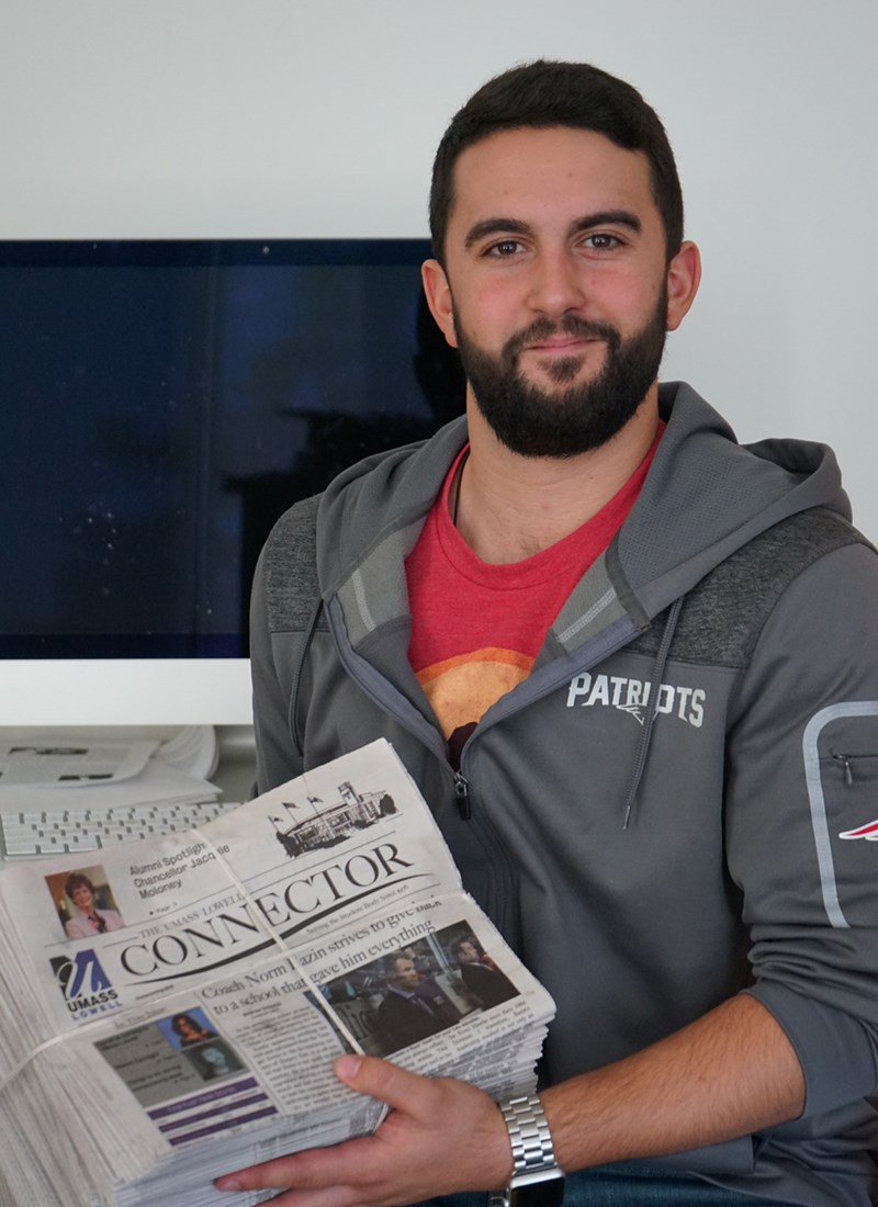 Headshot of Andrew Sciascia holding a stack of The Connector newspapers