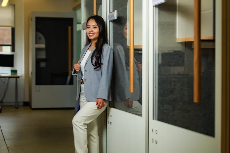 Paola Carchi stands in hallway leaning on glass door