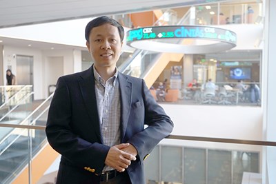 Assoc. Prof. Hieu Phan stands in front of the stock ticker at the business school