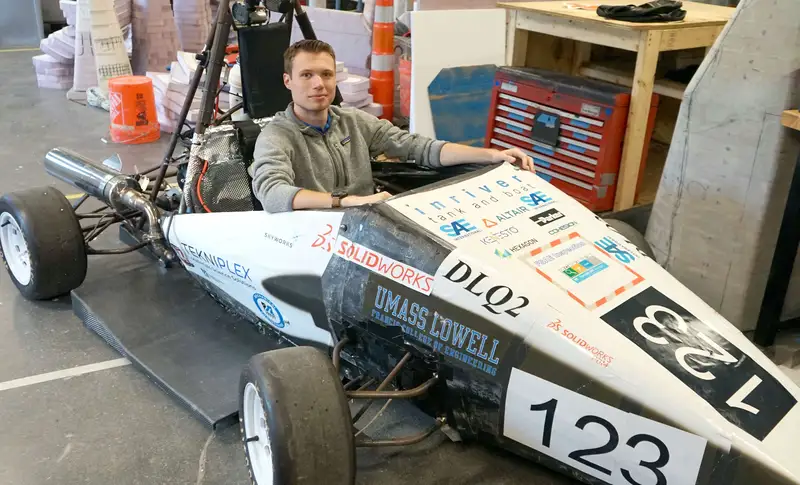 Liam Clancy sits in an open-wheel, formula-style race car he helped design and build with River Hawk Racing at UMass Lowell.