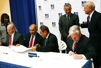 Shown signing the agreement are, from left, Stephen Murphy, vice president of contracts for Raytheon Integrated Defense Systems; Sanjay Kapoor, Raytheon vice president of Integrated Air and Missile Defense; GUST President Shuaib Shuaib; and UMass Lowell Chancellor Marty Meehan. Looking on are Marcellette Williams, UMass System senior vice president for academic and student affairs and international relations; Abdul-Rahman S. Al-Muhailan, chairman of GUST&rsquo;s board of trustees; and UMass Lowell Provost Ahmed Abdelal.