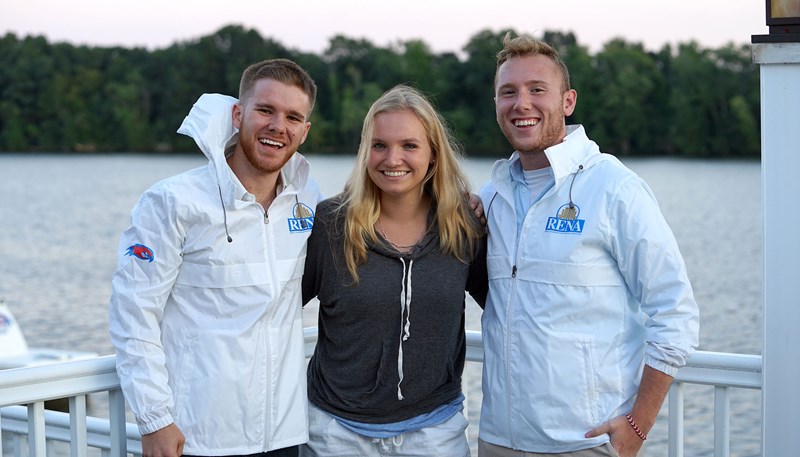 Josiah Gennell, left, and a young blonde woman and blond man stand on a dock