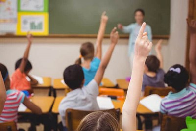 Kids raising their hands in classroom