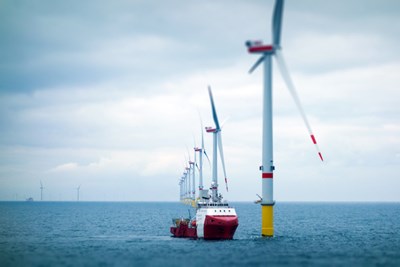 A shape sails past wind turbines in the ocean