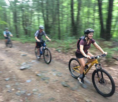 A partially blurry photo of 3 people riding bikes in the woods. Bicycling is currently growing in popularity at UMass Lowell.  Our goal is to foster a culture of responsible cycling during a time when habits are forming for maturing riders. A responsible cyclist follows the law, is considerate of others, communicates with others on the road, is conspicuous, predictable and utilizes appropriate equipment to ensure the safety of themselves and others.