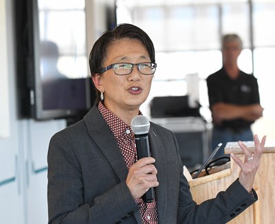 Chancellor Julie Chen addresses a crowd with a microphone in her right hand