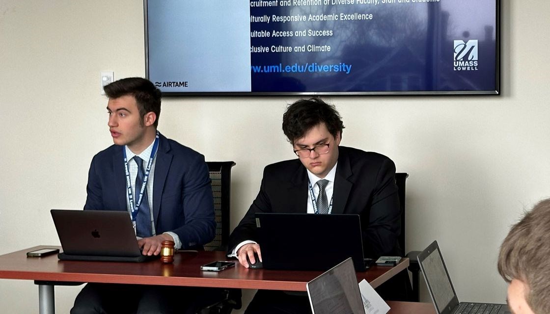 Anthony Amatucci sits at a table with an open laptop and gavel during a UMass Lowell Model United Nations meeting.