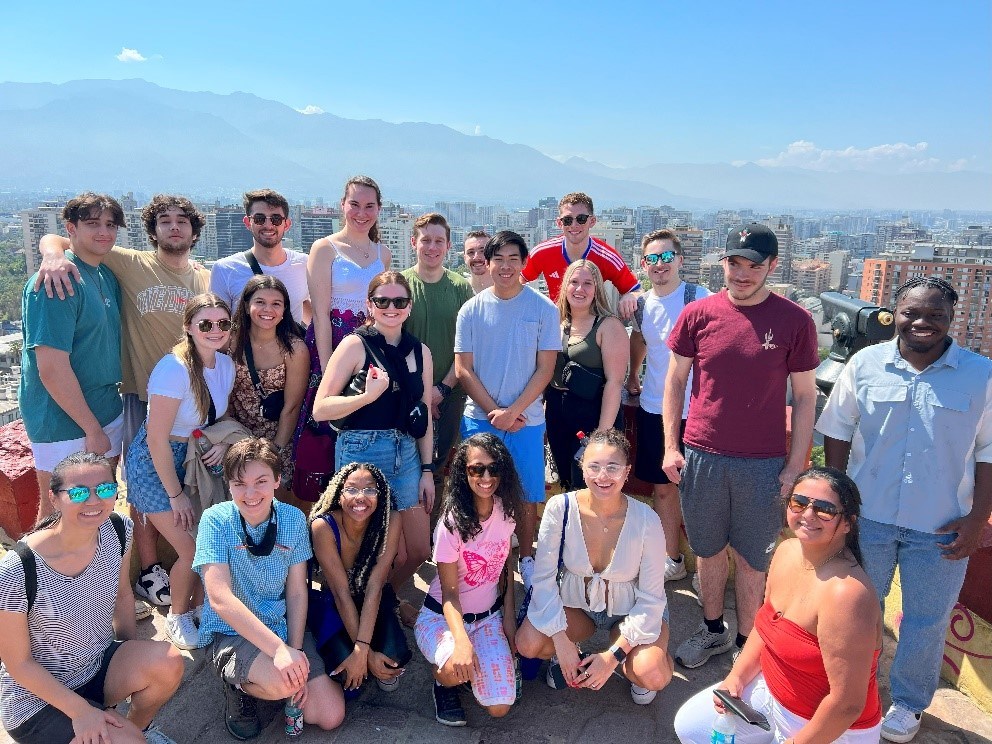 Students pose for photo in Chile with city in background.