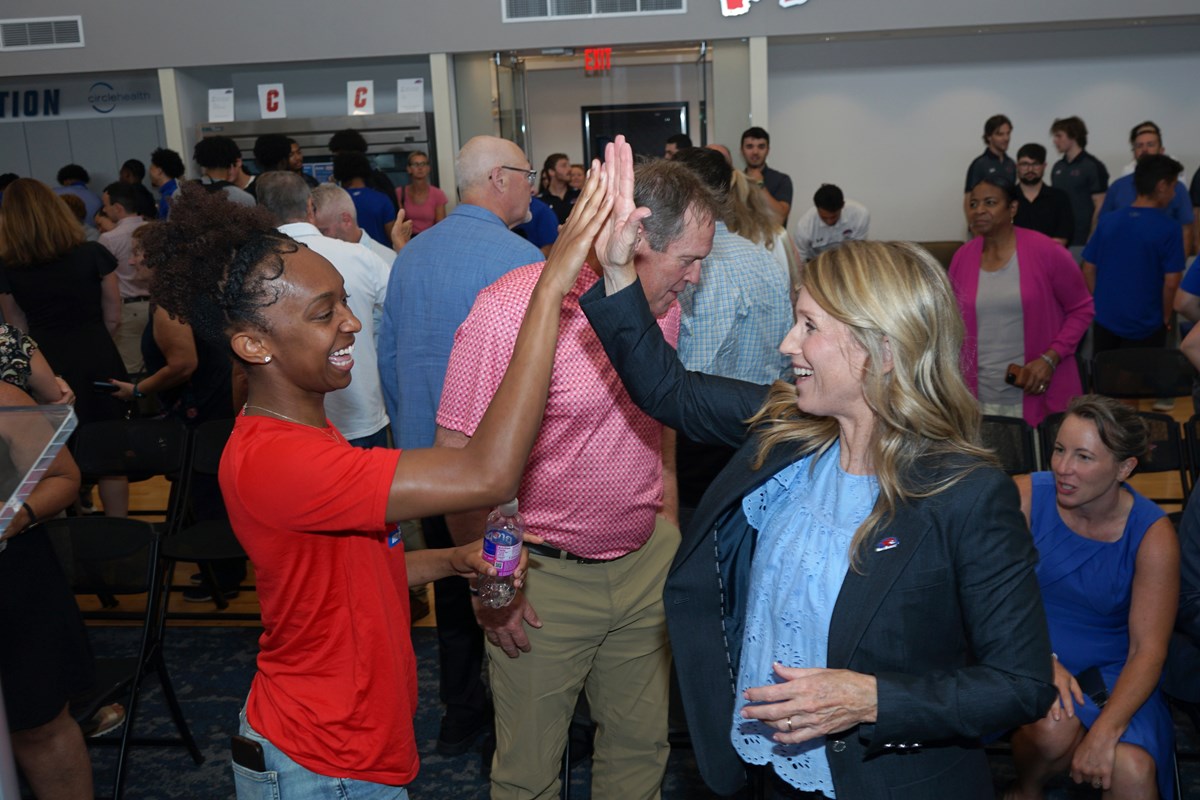 Two people high-five each other in a crowded room.