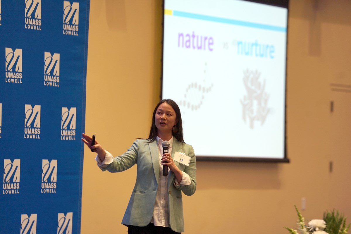 Faculty member holding a mic presenting a keynote speech.