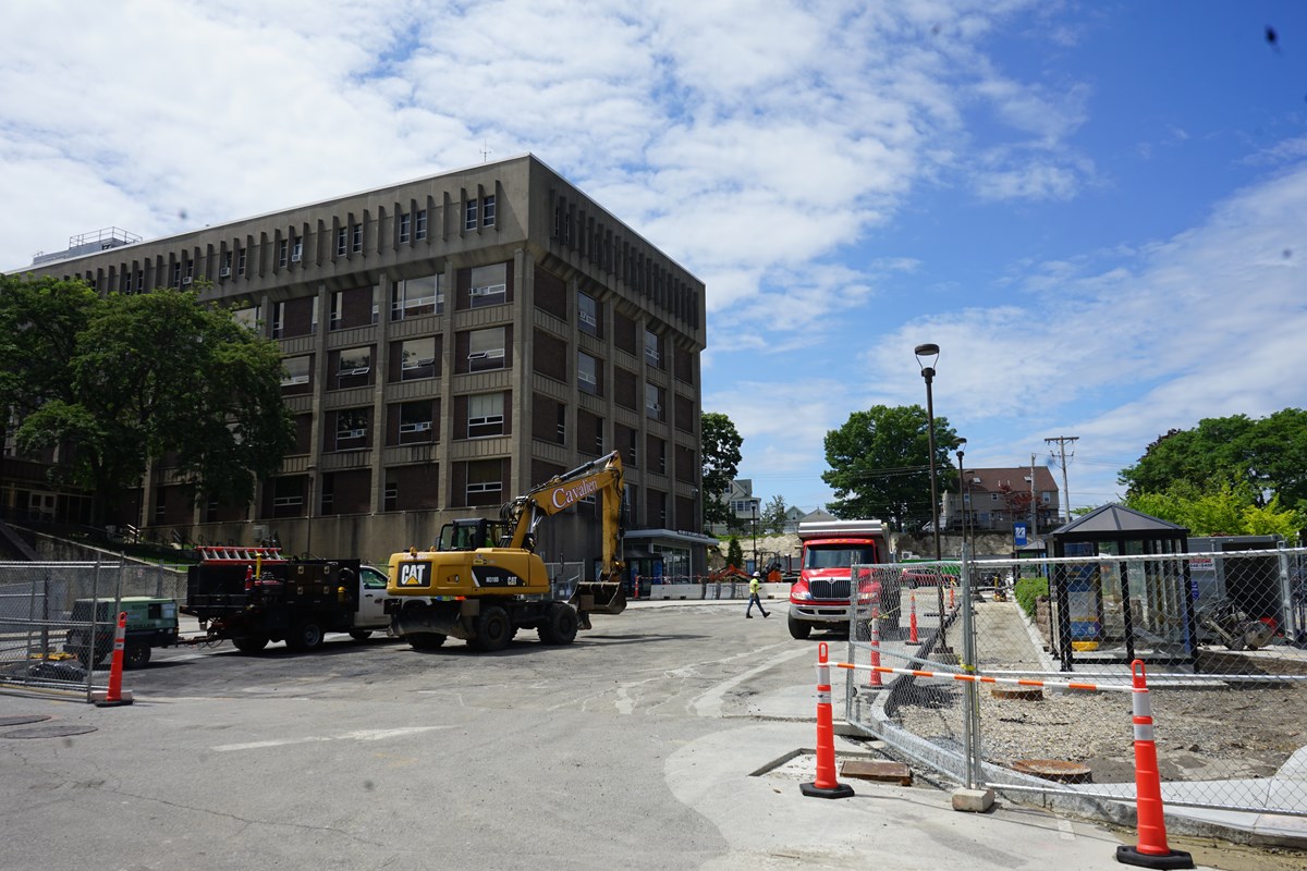 Construction trucks parked outside of a building next to a new bus stop.