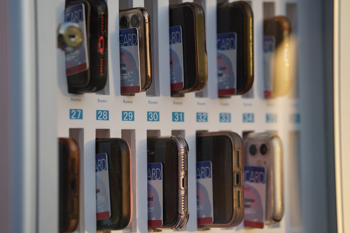 A closeup of two rows of phones and student IDs being stored in a special box.