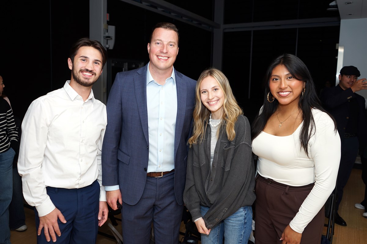 Two men and two women smile as they pose for a photo in an auditorium.