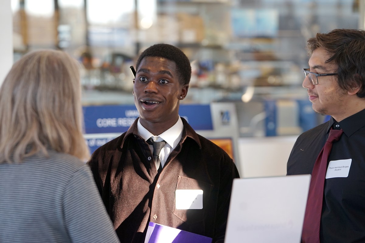 A student reacts while talking to a woman in a room while another student looks on.