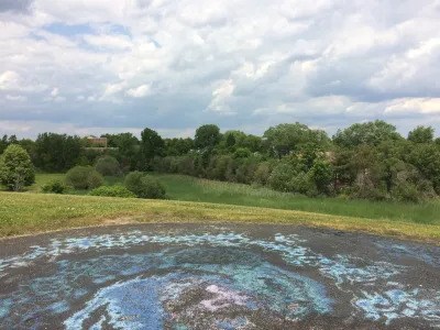 Swirly dirt pattern in field with grass and trees in background