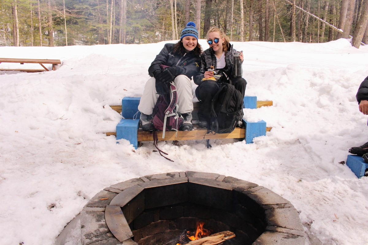 Two Women at a Daytime Campfire in the Snow