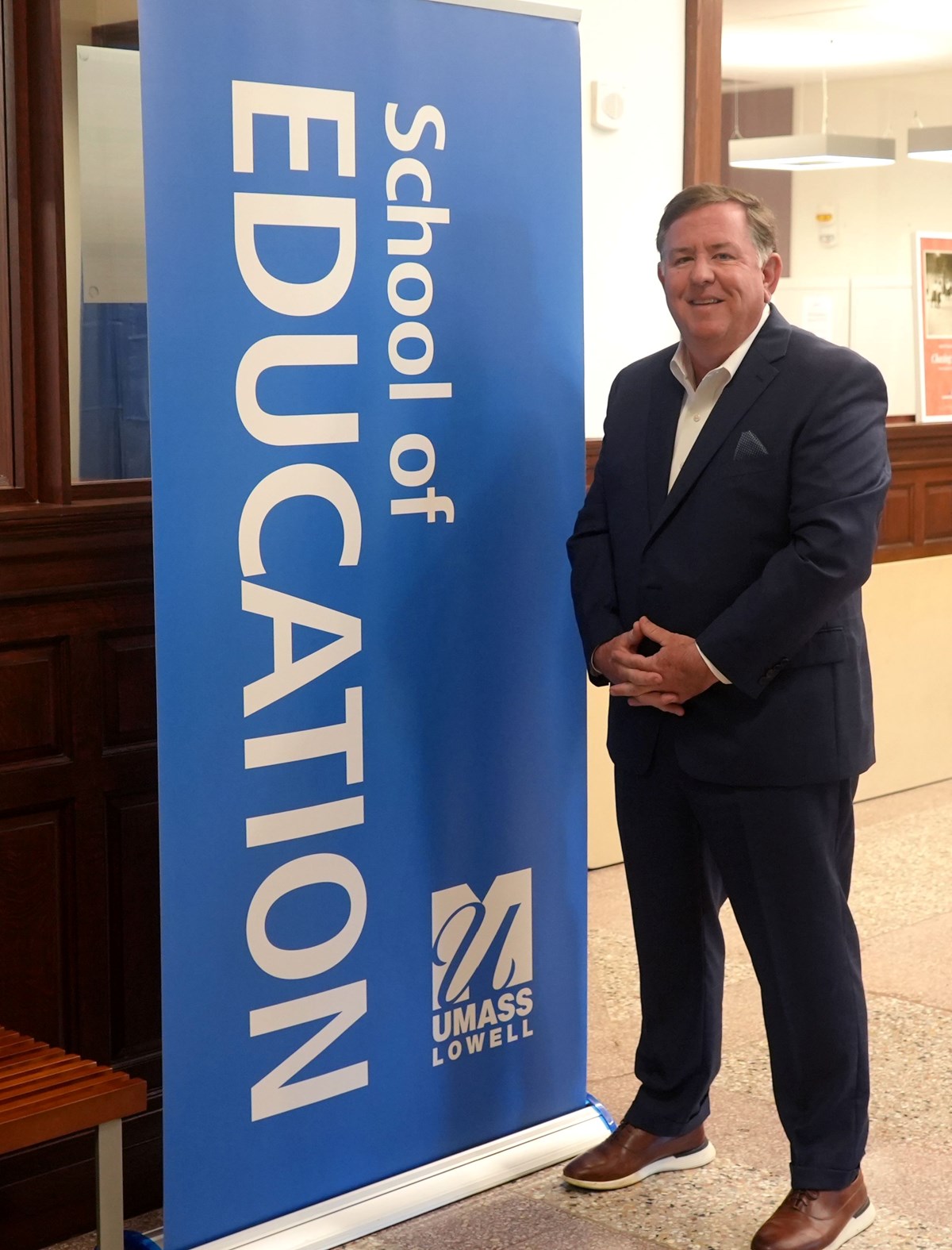 Jay Lang next to School of Education UMass Lowell sign.