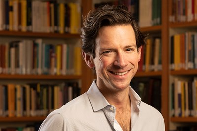 Philosophy Professor John Kaag in front of a bookshelf