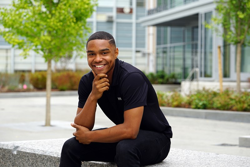 Kevin Akers sits on a bench outside on UMass Lowell's North campus outside Perry Hall