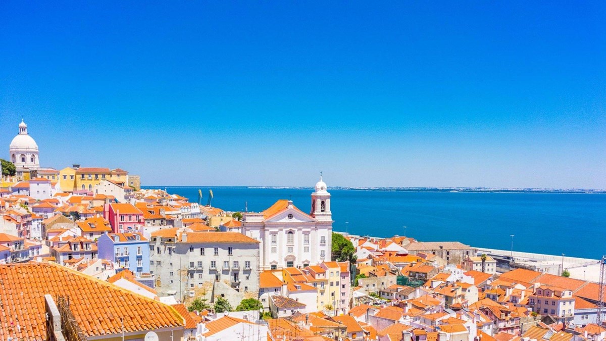 Lisbon port with buildings and ferry on the blue ocean.