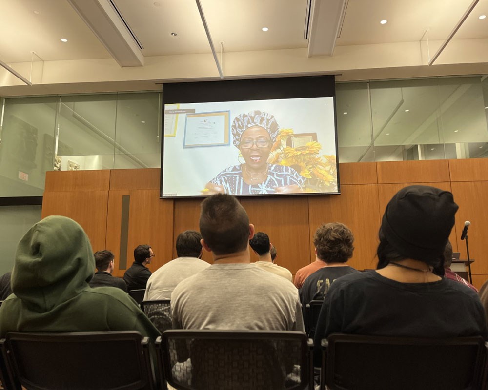 UMass Lowell students look up at a screen to video chat with the creator of the movie "Maka."