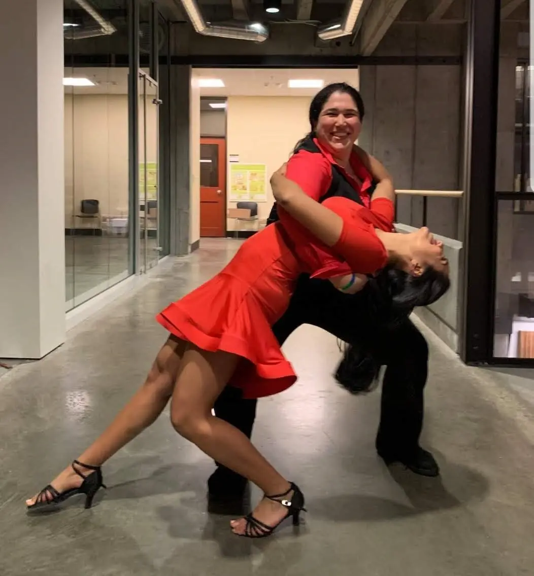 Two people dressed in red pose for a photo while salsa dancing.