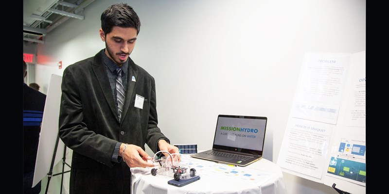 Sarvesh Handa standing with his project's prototype and idea plan model.