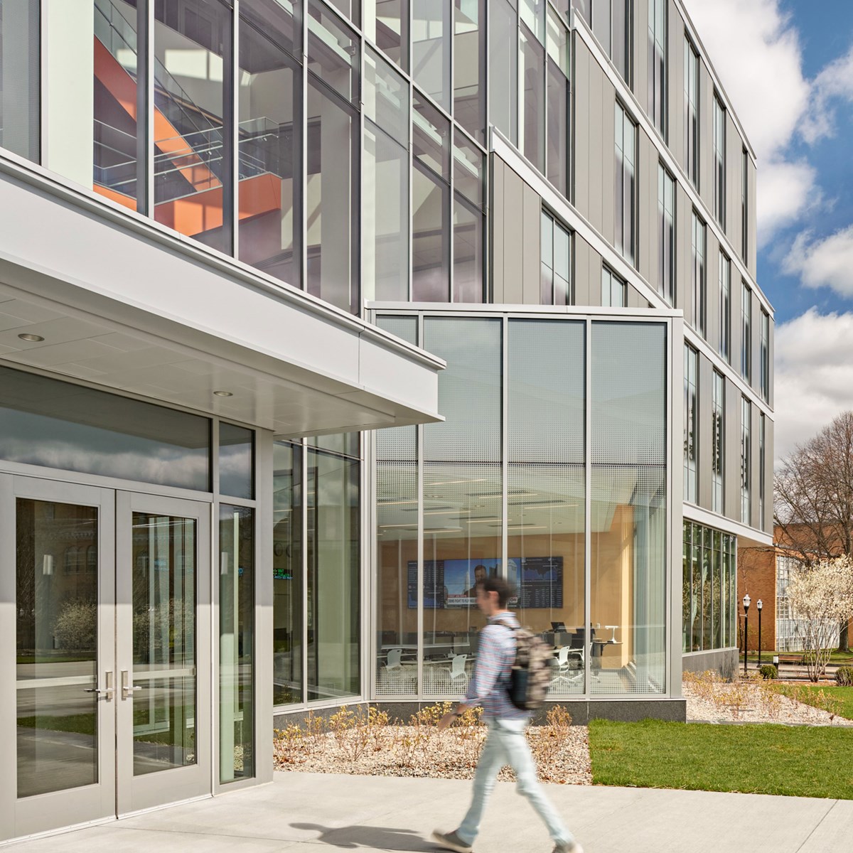 A student walking into the front entrance of the Pulichino Tong Business Center.