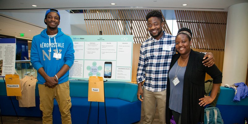 Hylton Carboo, Cassandra Francois and Bernard Tay smile by their T.A.P. poster at a DifferenceMaker event