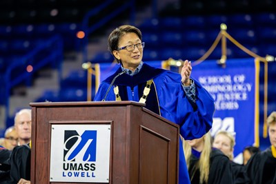 Hundreds of students stand in an arena during a convocation ceremony.