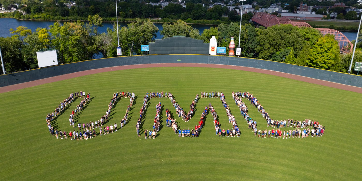 UML spelled out on field with students