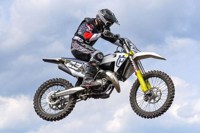 Alumni Tom Miller in mid-air, with a dirt bike against a clear sky.