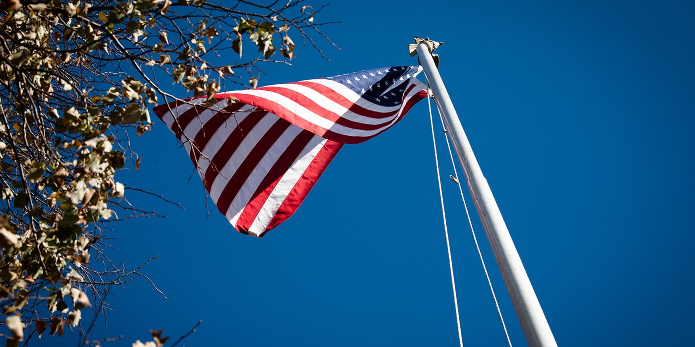 An American flag waving in the wind as seen from below.