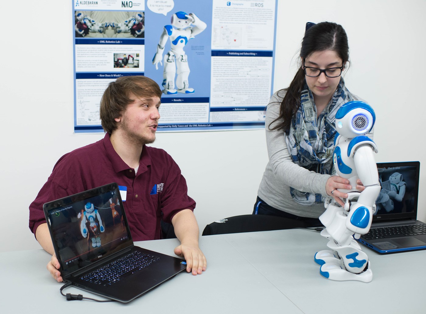 Two students work with a robot and laptop in the NERVE Center at UMass Lowell.