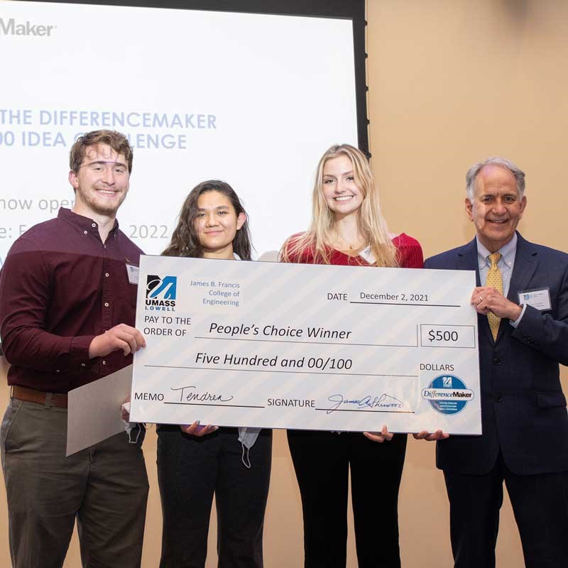 Three students and a professor hold an enlarged check for the People's Choice Winner at UMass Lowell DifferenceMaker competition.