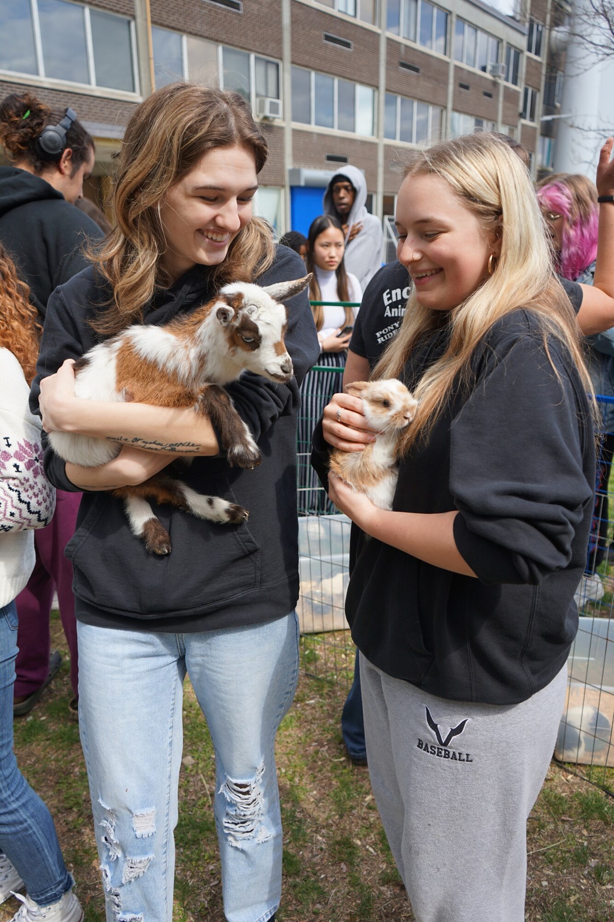 Two UMass Lowell students hold baby goats at petting zoo