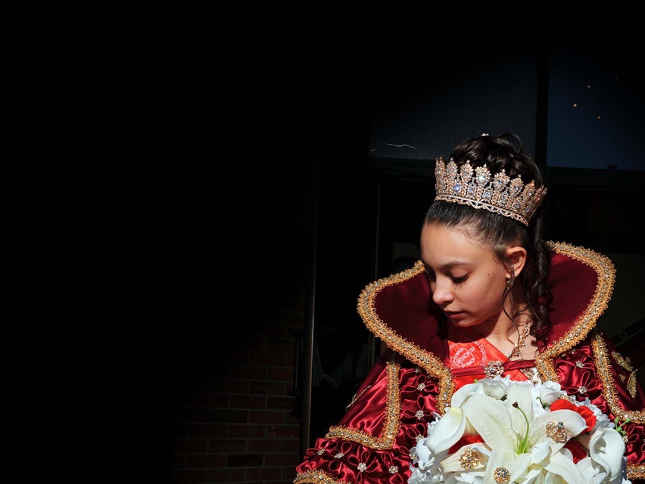 Young person with crown and holding bouquet in a fancy cape/dress. Queen of a Holy Ghost Feast.