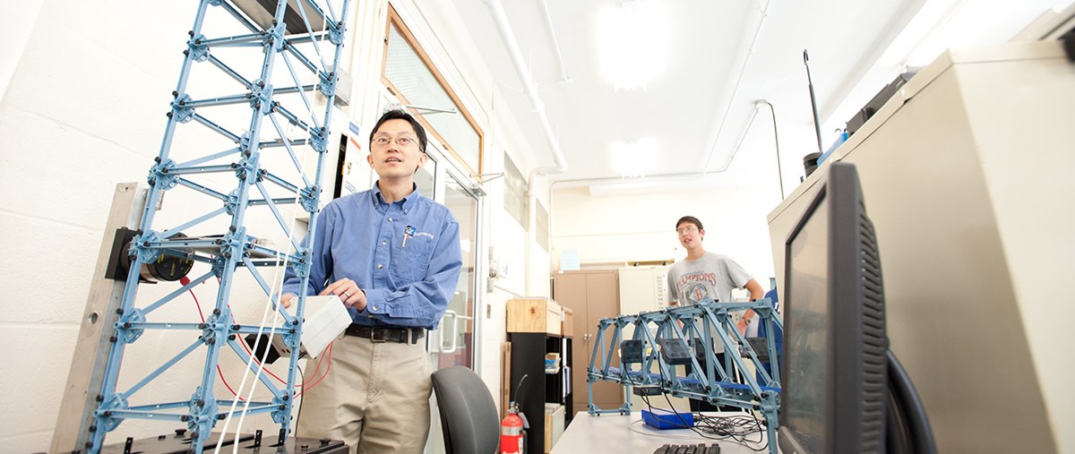 A UMass Lowell faculty member and student working on horizontal and vertical bridge models.