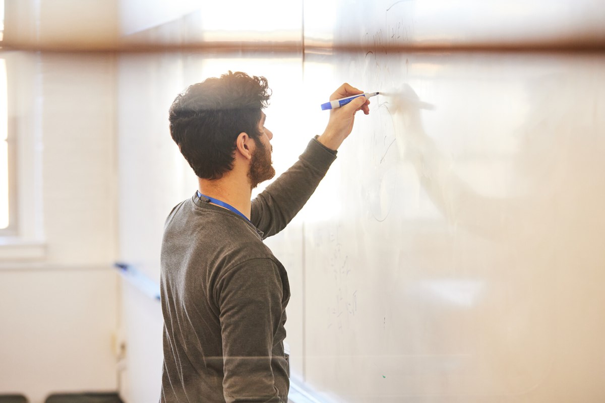 Man writes on white board in UMass Lowell classroom