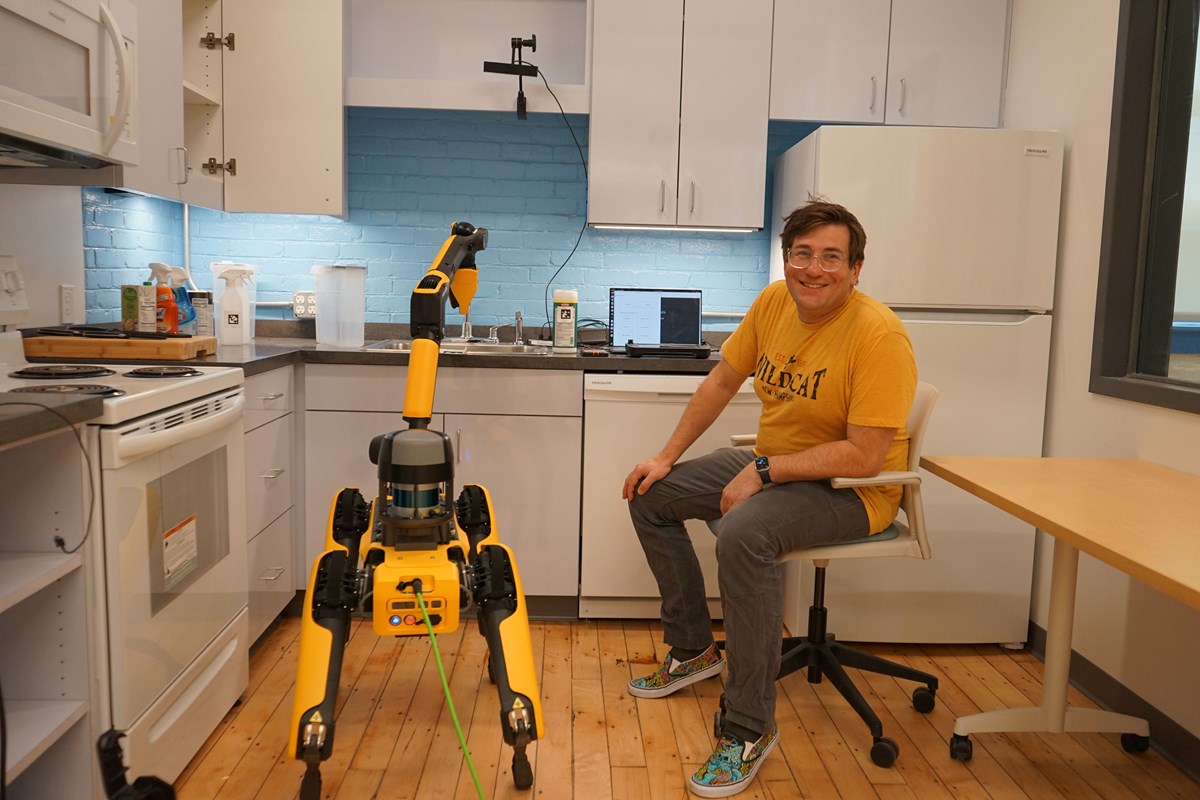 Russ Perkins seated in a kitchen with a yellow Boston Dynamics robot dog.