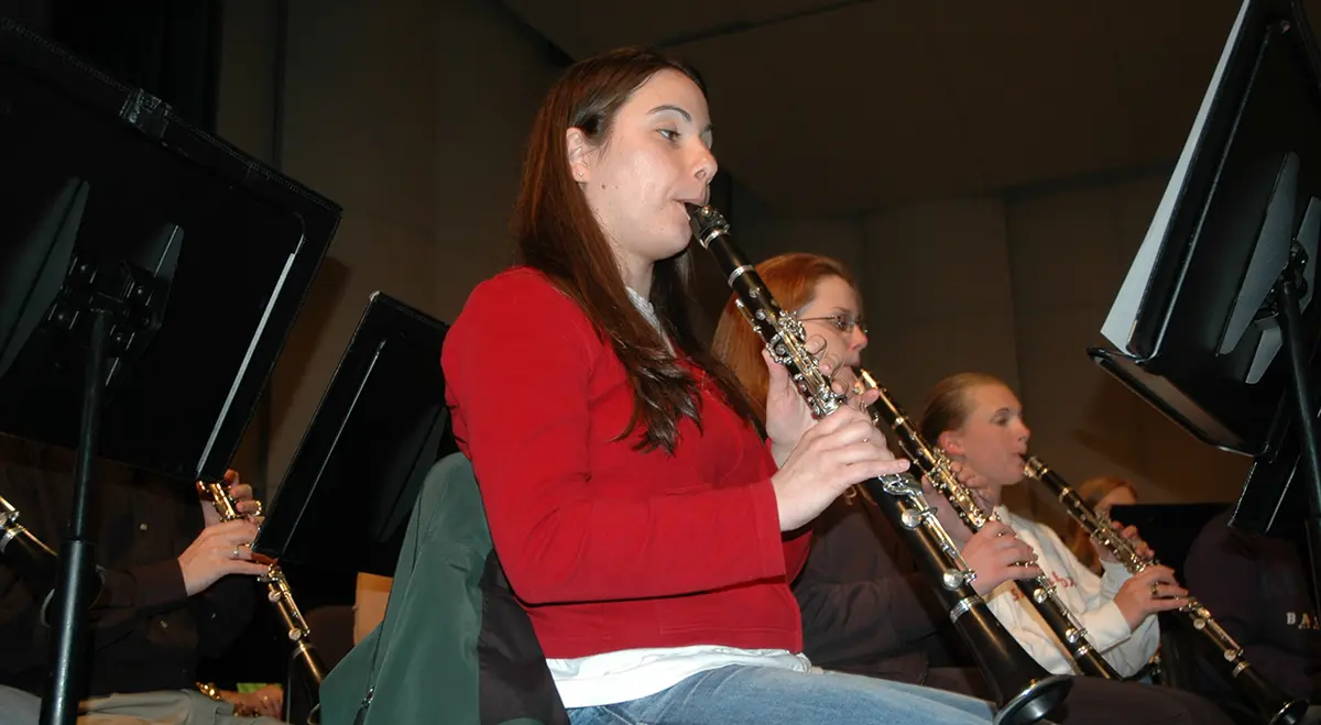 Three female students playing clarinets in a music class/rehearsal.