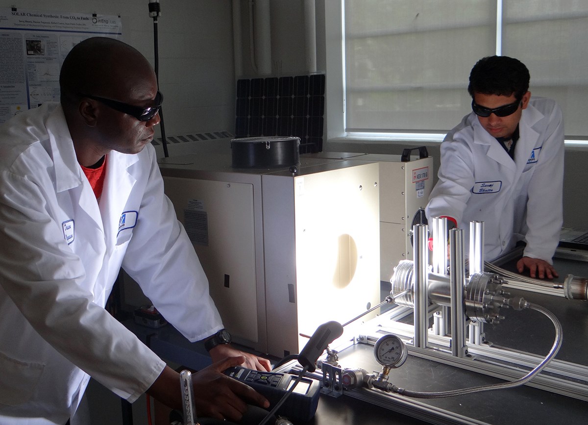 Two male students in lab coats working in the solar energy lab.