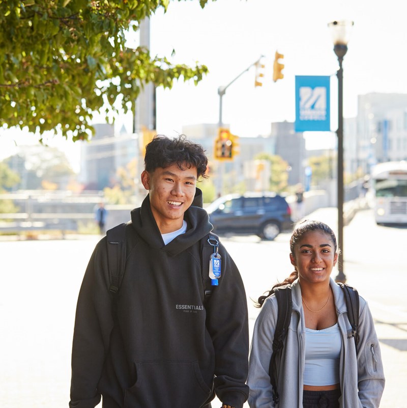 Male and female student walk on sidewalk on University Ave