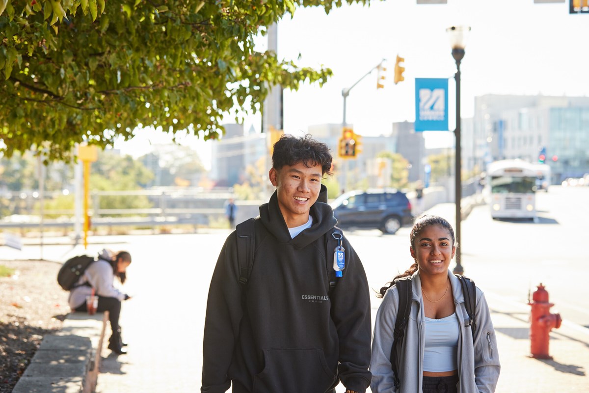 Male and female student walking on sidewalk