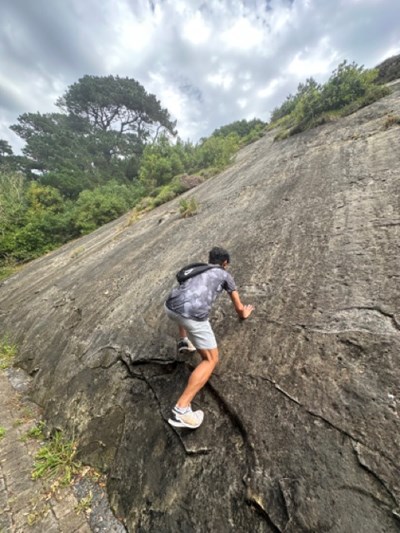 A UMass Lowell Study Abroad student climbs a rock on Monte Urgull in San Sebastian, Spain in 2024.